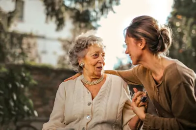 Two women laughing together in a sunlit garden