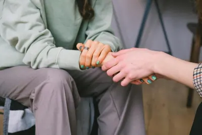 Two people clasping hands warmly across a table in a moment of support